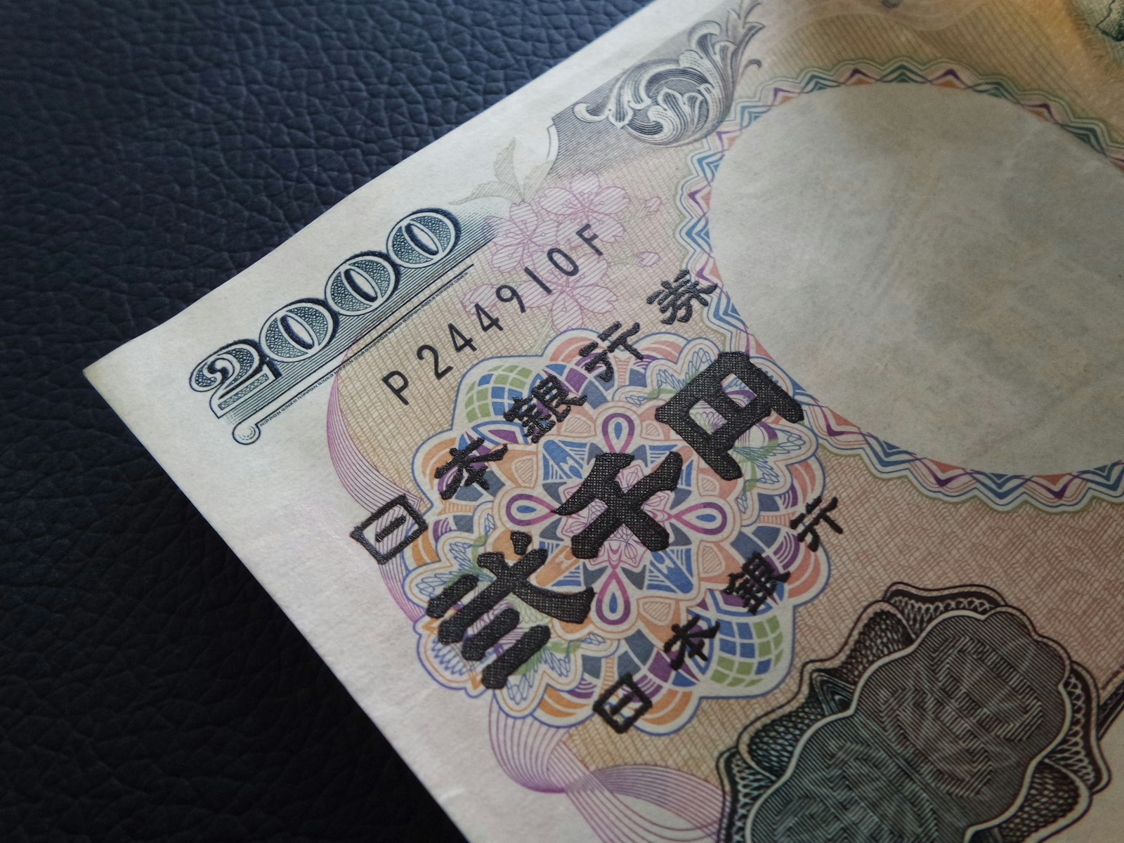 Close-up of a Japanese 2,000-yen banknote on a dark leather surface